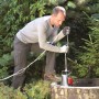 Mann bedient Einhell Schmutzwasserpumpe GC-DP 1020 N am Brunnen. Fördermenge 18.000 l/h.