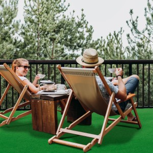 Grüner Primaflor Rasenteppich Park auf Balkon mit entspannten Personen in Liegestühlen.