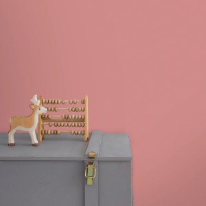 Little Dutch Wandfarbe Pure Pink: Rosa Wand mit Spielzeug-Deko auf grauer Truhe.