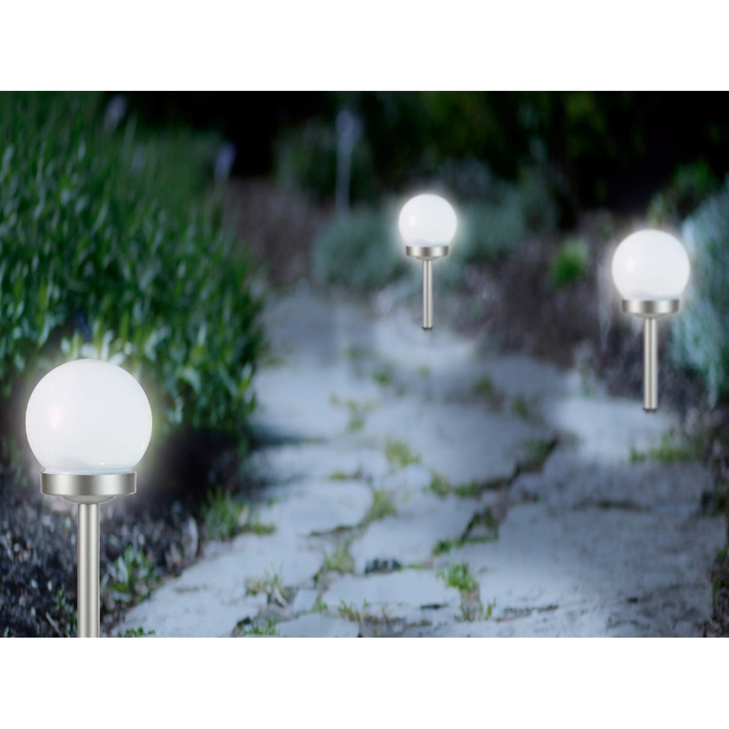 Dekorative Solar-Kugeln mit Erdspieß in Weiß-Silber entlang eines Gartenwegs.