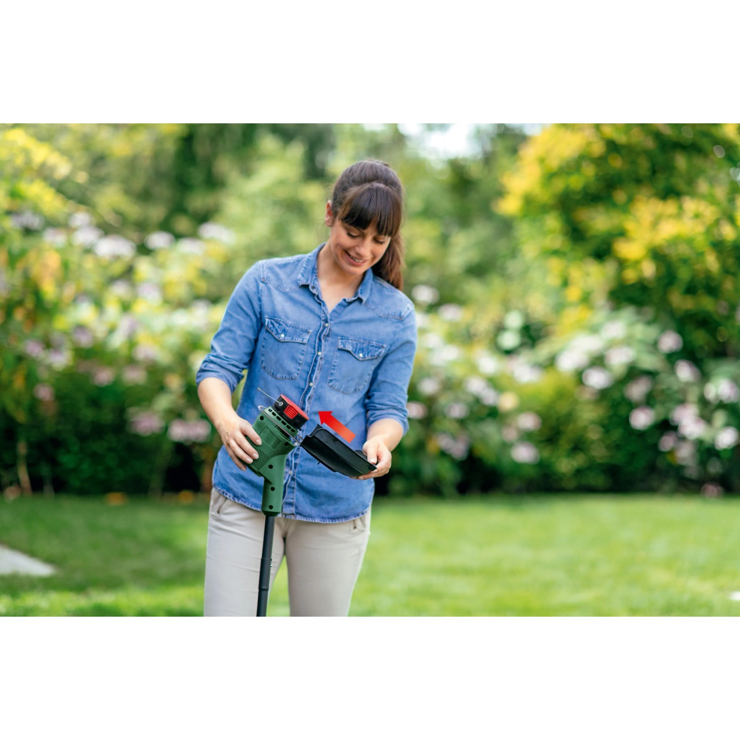 Frau wechselt Spule am Bosch Akku-Rasentrimmer EasyGrassCut 18V-230 im Garten.
