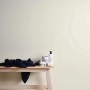 Cremefarbene, matte Uni-Tapete von PROFHOME an Wand, kombiniert mit Deko auf einer Holzbank.