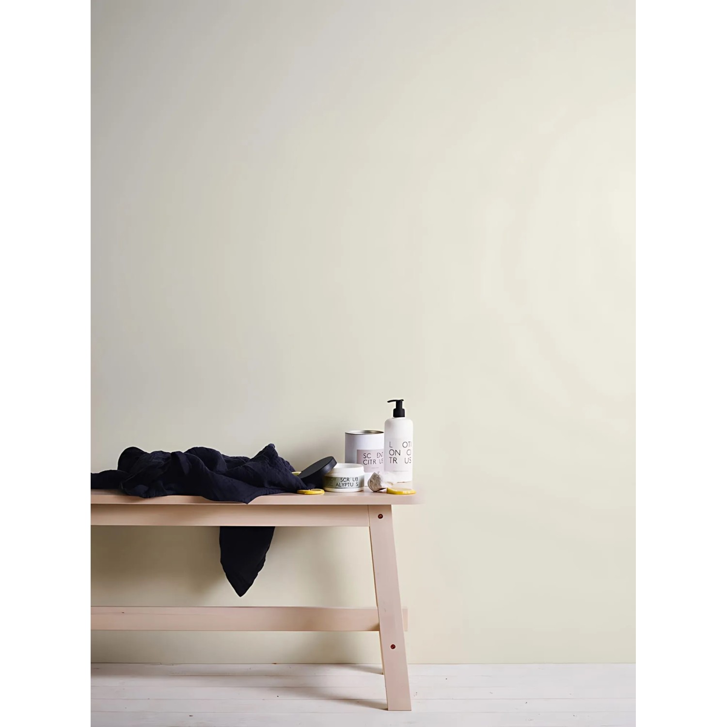 Cremefarbene, matte Uni-Tapete von PROFHOME an Wand, kombiniert mit Deko auf einer Holzbank.