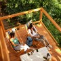 Zwei Frauen entspannen auf einer Holzterrasse, die mit Bondex Wetterschutz-Öl Teak behandelt wurde.