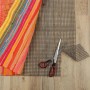 Dunkelgrauer ProHome Teppich Gleitschutz (80x150 cm) mit Schere auf Holzboden.
