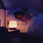 WiZ LED-Tischleuchte Hero neben schlafendem Kind im Bett, warmes Licht.