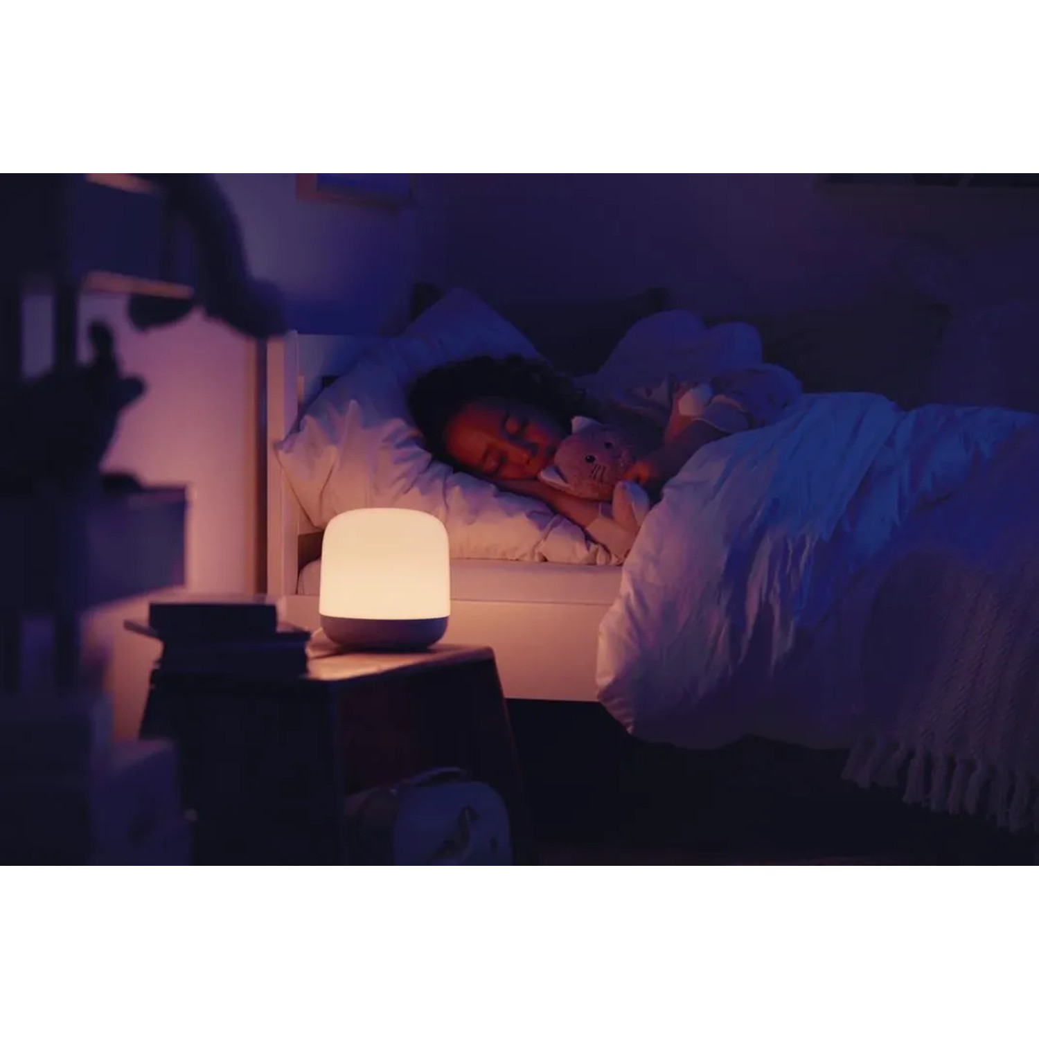 WiZ LED-Tischleuchte Hero neben schlafendem Kind im Bett, warmes Licht.