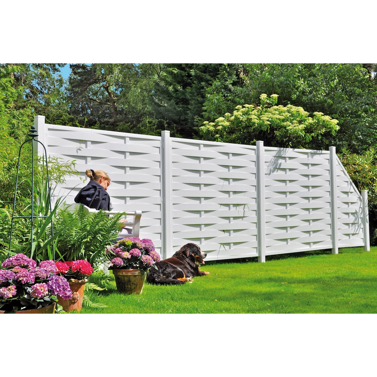 Weißer Kunststoff-Lamellenzaun Lightline (180x180cm) im Garten mit Hund und Blumen.