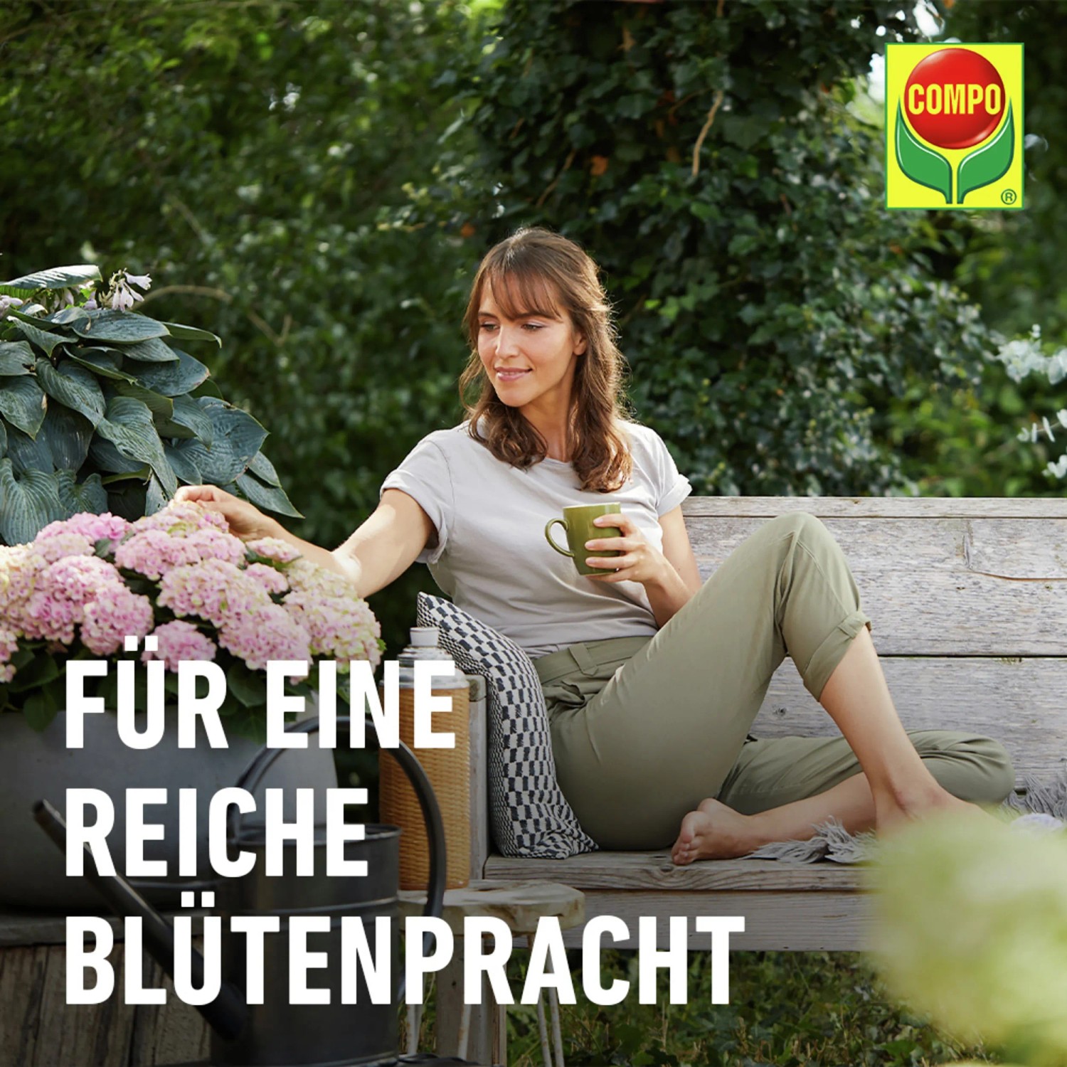 Frau auf Bank mit Compo Düngestäbchen für Balkonpflanzen, üppige Blütenpracht im Garten.