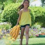 Mädchen trägt gelben Hozelock SuperHoze Expansions-Gartenschlauch (15m) im Garten.