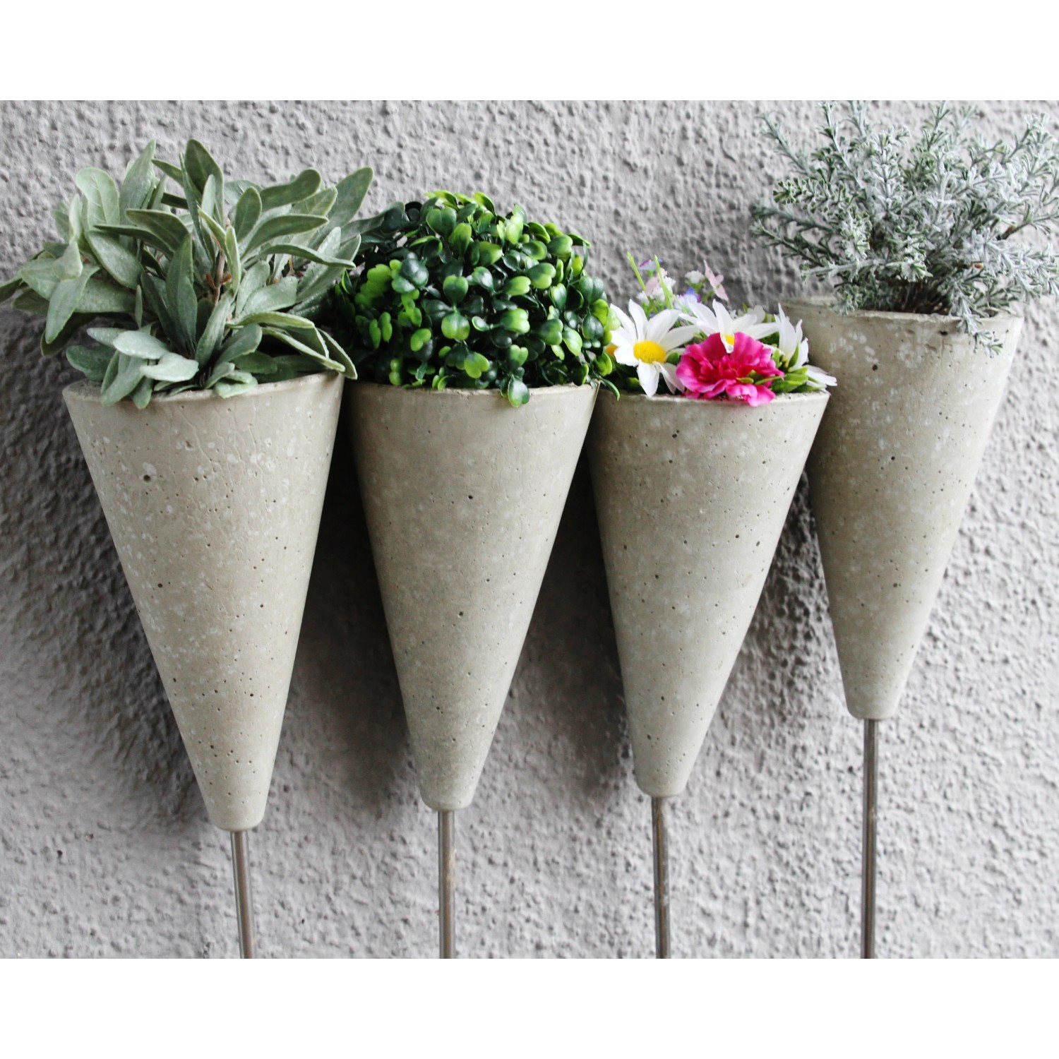 Vier bepflanzte, hellgraue Ultrament Bastel Beton Kegel als Deko für den Garten oder die Wohnung.