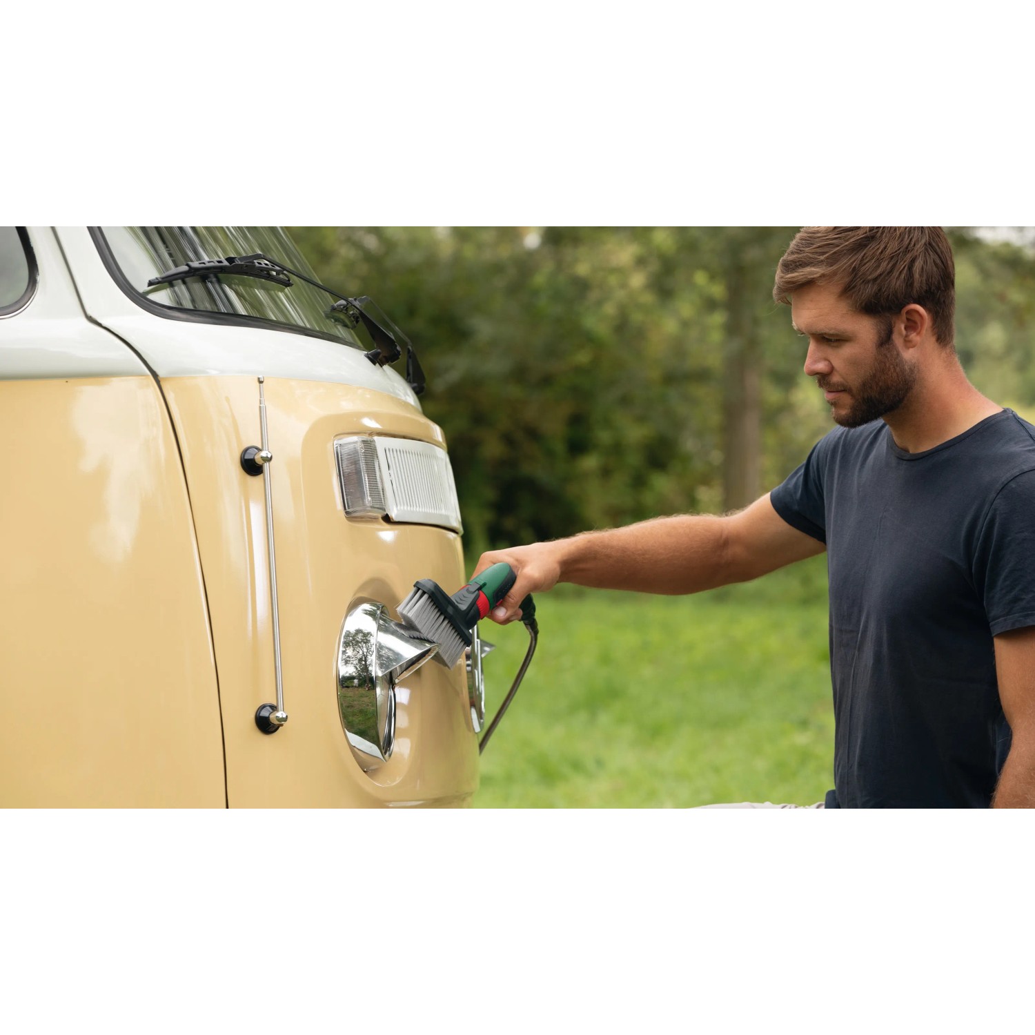 Mann reinigt VW Bulli mit Bosch Akku-Druckreiniger Fontus 18V mit Bürste.