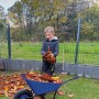 Pro-Bau-Tec Kinderschubkarre (Blau, 20 l) mit Kind beim Laub sammeln im Garten.