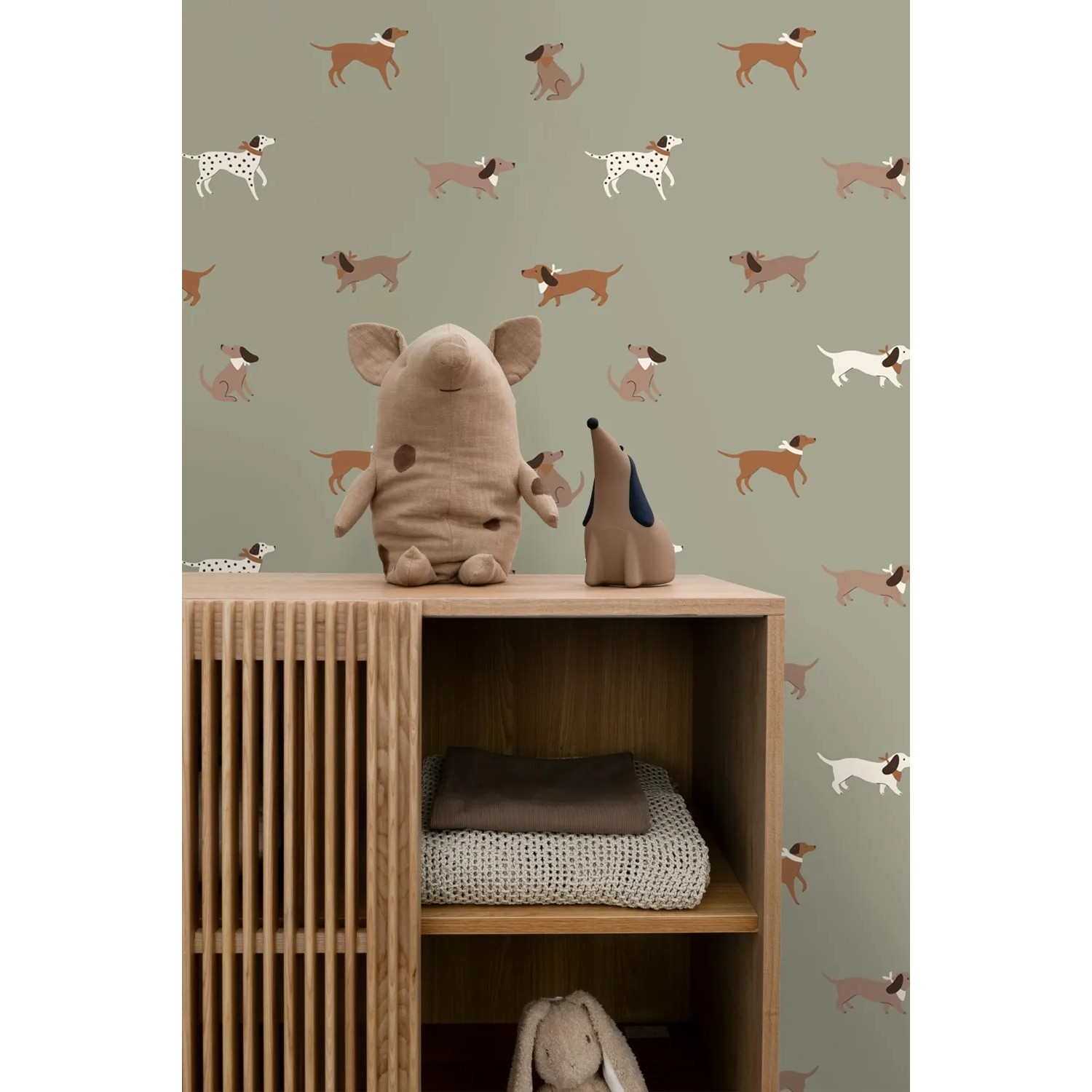 ESTAhome Vliestapete mit braunen und grünen Hundemotiven an einer grünen Wand im Kinderzimmer.