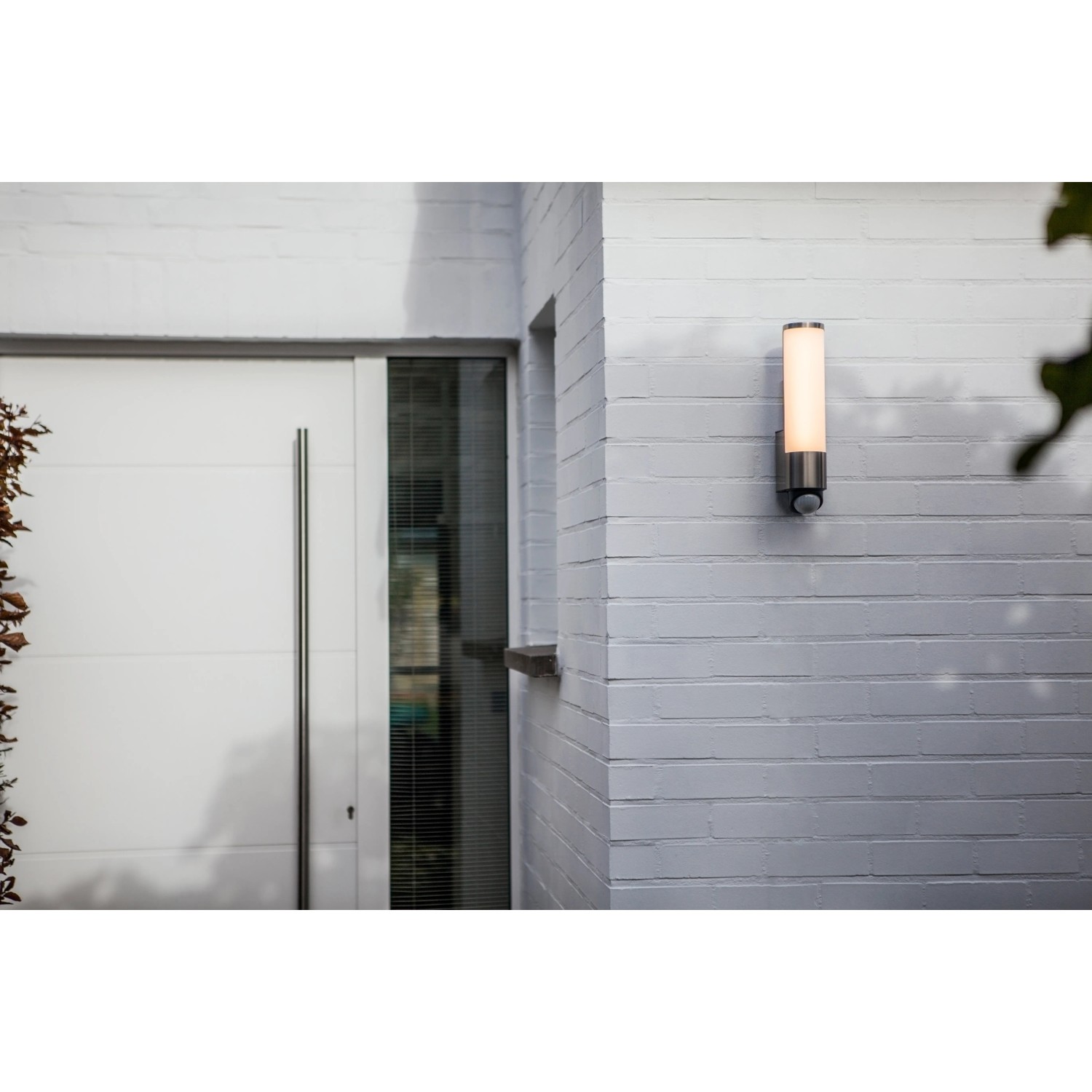 Moderne Lutec LED-Außenwandleuchte Leda mit Bewegungsmelder an grauer Hauswand.