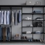 Schwarze Metall-Kleiderstange (60cm) in Regalsystem mit Kleidung und Accessoires.