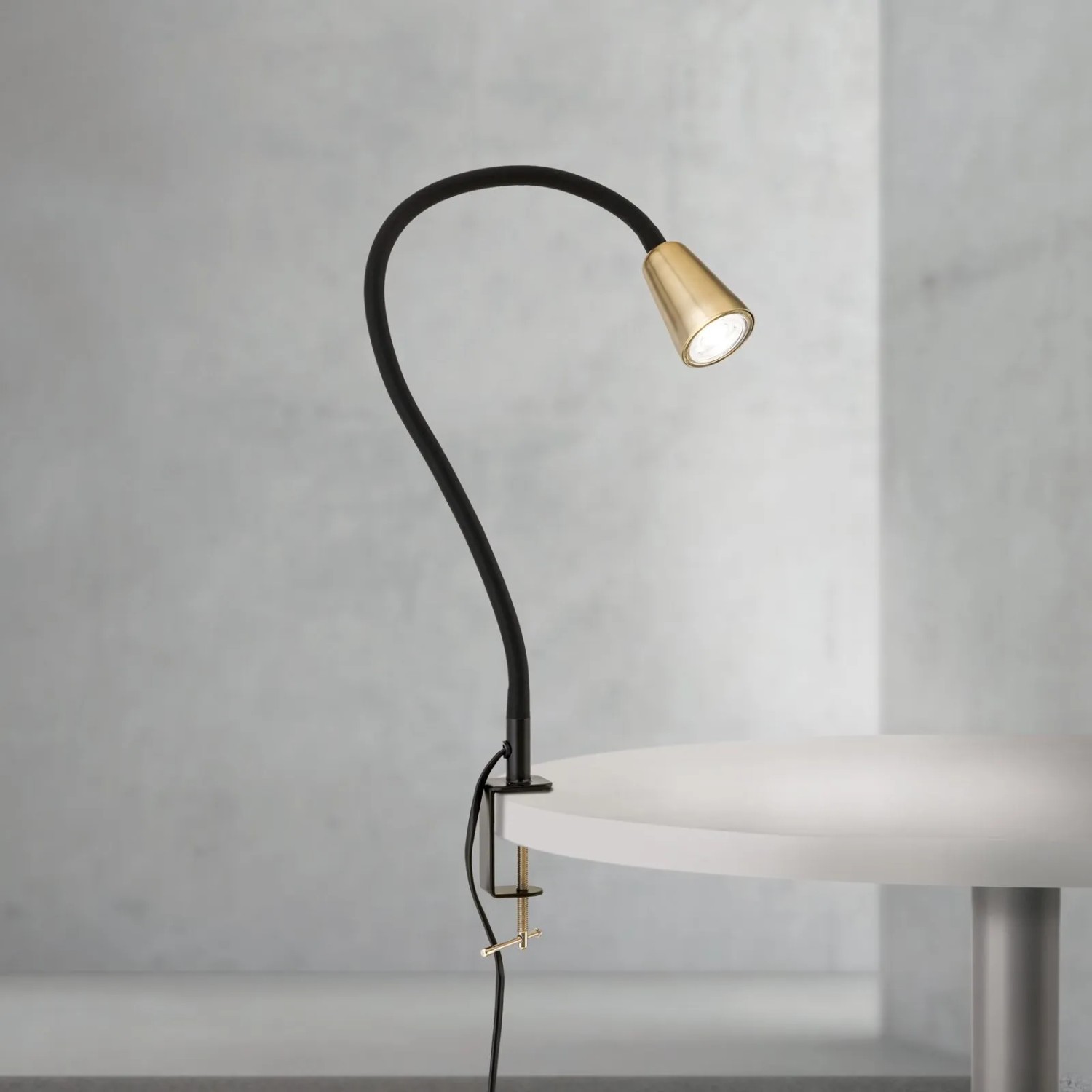 Orion Dotty Klemmleuchte, schwarz-gold, mit flexiblem Schwanenhals, an Tisch geklemmt. Moderne GU10 Innenleuchte.