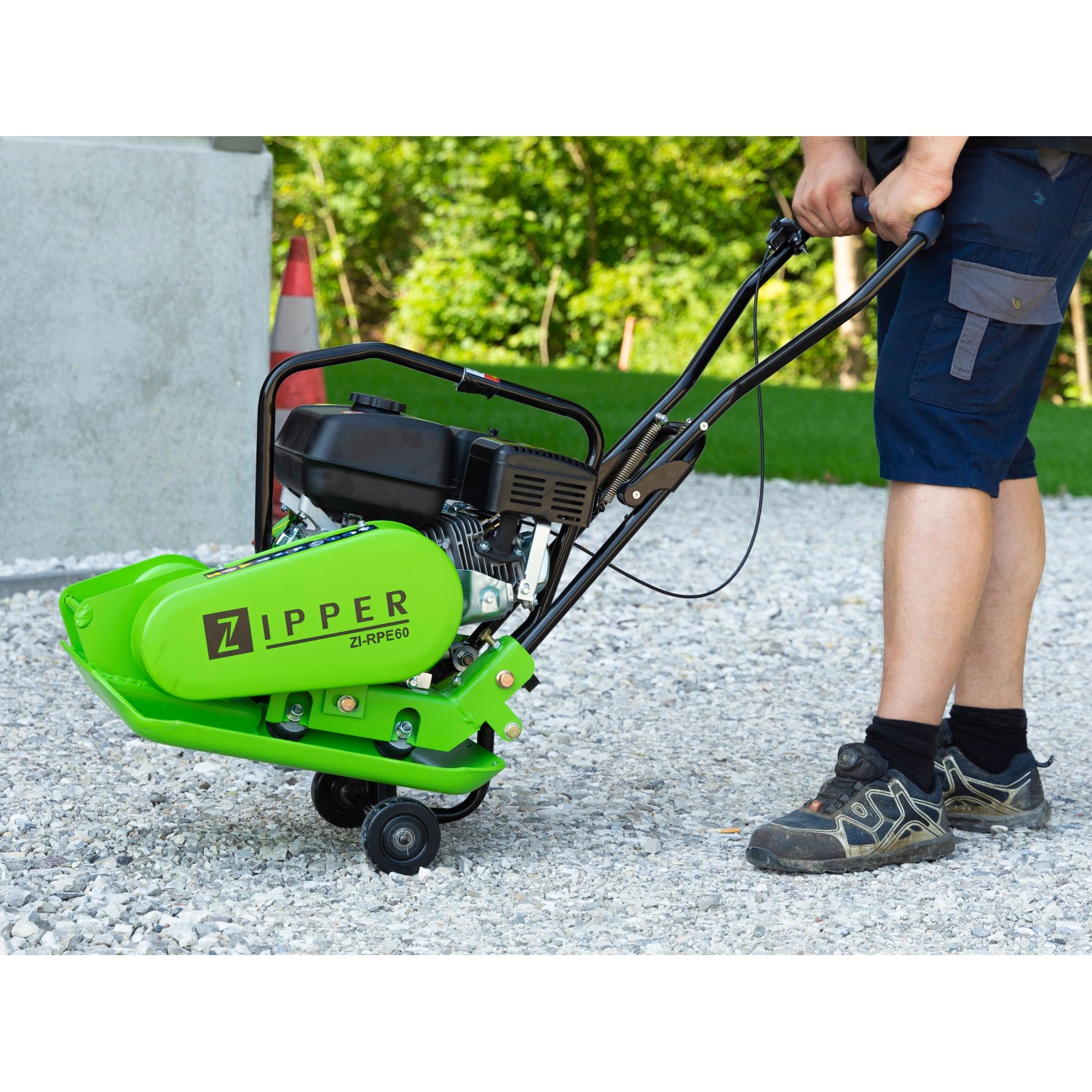 Grüne Zipper Rüttelplatte ZI-RPE60 mit Bediener im Einsatz zur Bodenverdichtung. Baumaschine mit Fahrwerk.