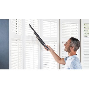 Mann reinigt Jalousien mit Shark Akku-Handsauger WV200EU. Kompakter Handstaubsauger.