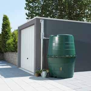 Grüne Garantia Zisterne Top-Tank 1300 l zur Regenwassernutzung im Garten vor Garage.