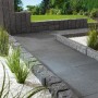 Anthrazit-graue Terrassenplatten aus Naturstein (60x60x3 cm) auf Terrasse mit Randsteinen und Dekosteinen.