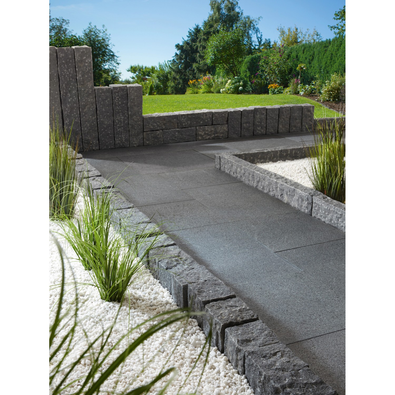Anthrazit-graue Terrassenplatten aus Naturstein (60x60x3 cm) auf Terrasse mit Randsteinen und Dekosteinen.