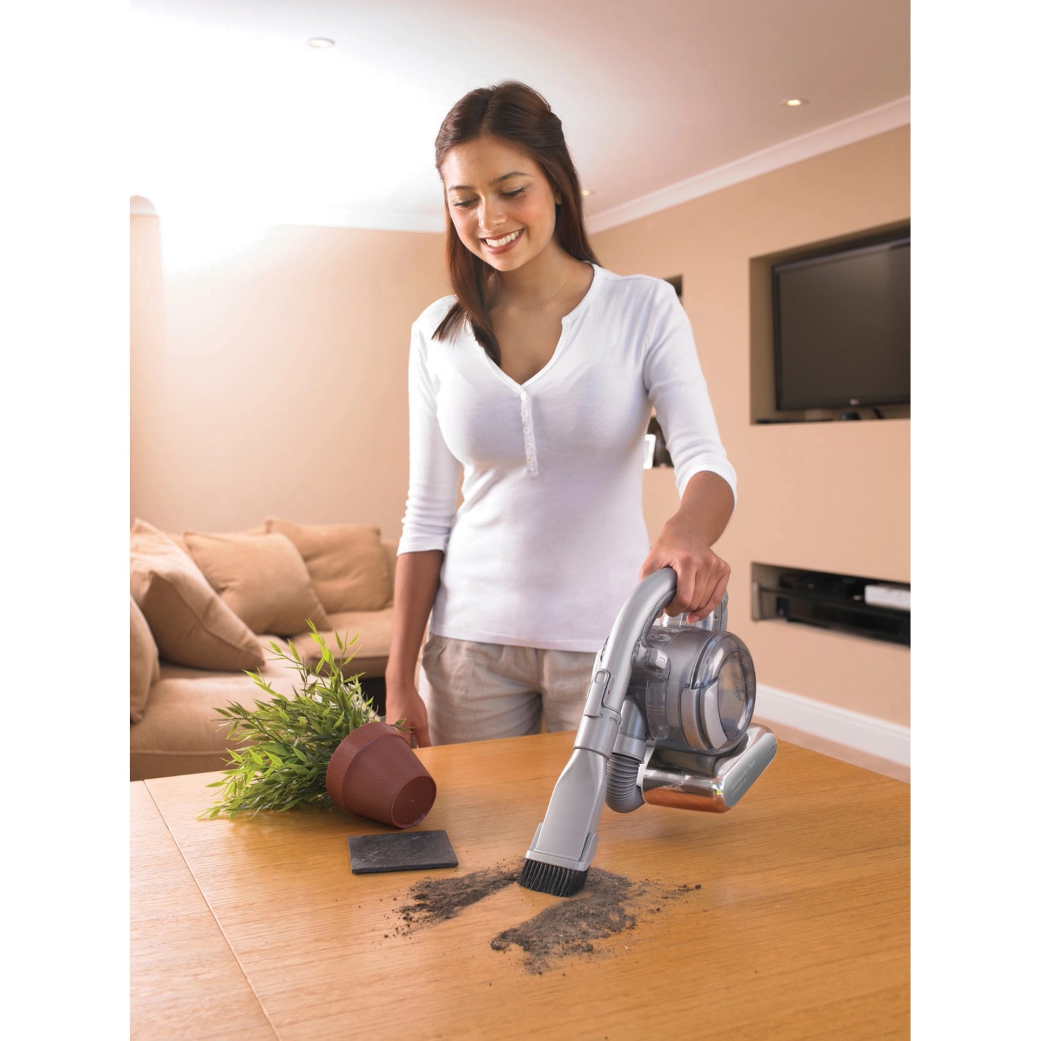 Frau saugt Tisch mit Black+Decker Akku-Handstaubsauger Dustbuster Flexi PD1820L.