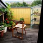 Relaxdays Balkongewächshaus aus grünem Stahl und transparentem PVC mit Pflanzen auf einem Holz-Balkon. Ideal zur Anzucht.