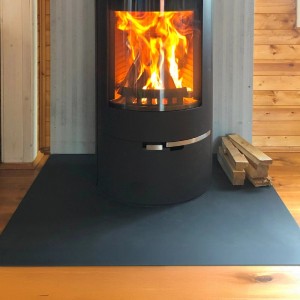 Schwarze Tulup Funkenschutzplatte aus Metall unter Kaminofen. Brandschutz für den Boden.