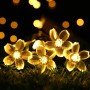 Warmweiße LED Solar-Lichterkette mit leuchtenden Kirschblüten auf Gras für festliche Gartenbeleuchtung.