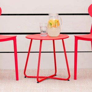 Runder, roter Metall-Beistelltisch für Garten und Balkon, mit Getränken und Stühlen.