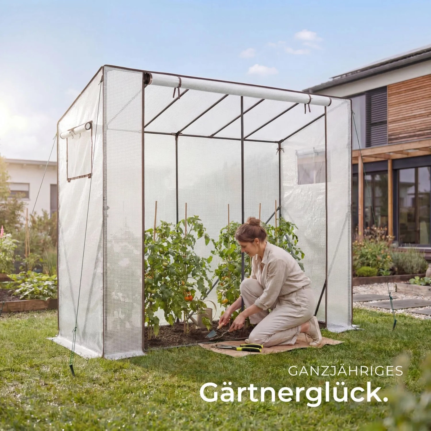 Transparentes Tectake Foliengewächshaus Anton im Garten. Eine Person pflegt Tomatenpflanzen. Wetterfest & UV-beständig.