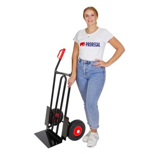 Schwarze PROREGAL Sackkarre Rhino XL mit Schaufel und pannensicheren Rädern neben einer Frau.