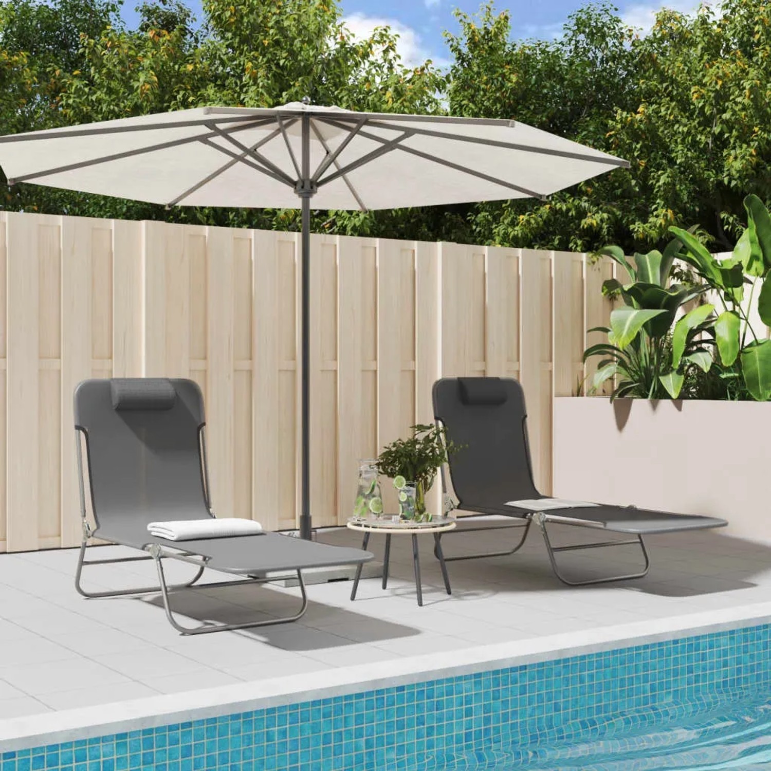 Zwei graue, klappbare Sonnenliegen aus Textilene und Stahl neben einem Pool mit Sonnenschirm.