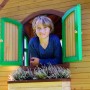 Kind im braun-grünen Axi Sarah Spielhaus mit grüner Fensterumrandung.