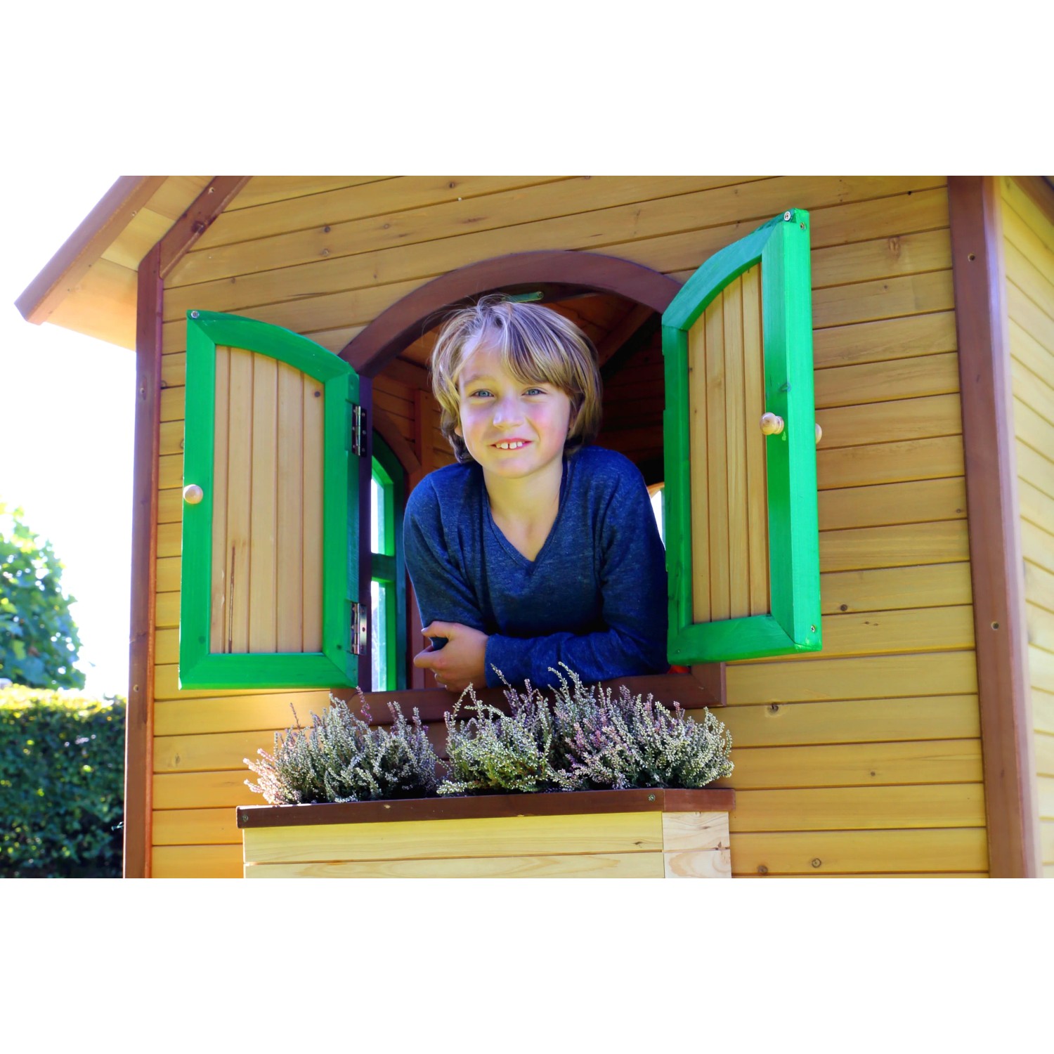Kind im braun-grünen Axi Sarah Spielhaus mit grüner Fensterumrandung.