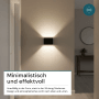 Schwarze LUXULA Akku Wandleuchte mit Up-Downlight Effekt und Bewegungssensor an einer Wand.