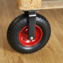 Schwarze, luftbereifte Bockrolle mit roter Felge und Stahlhalterung, an Holzpalette montiert. Schwerlastrolle für Transportwagen.
