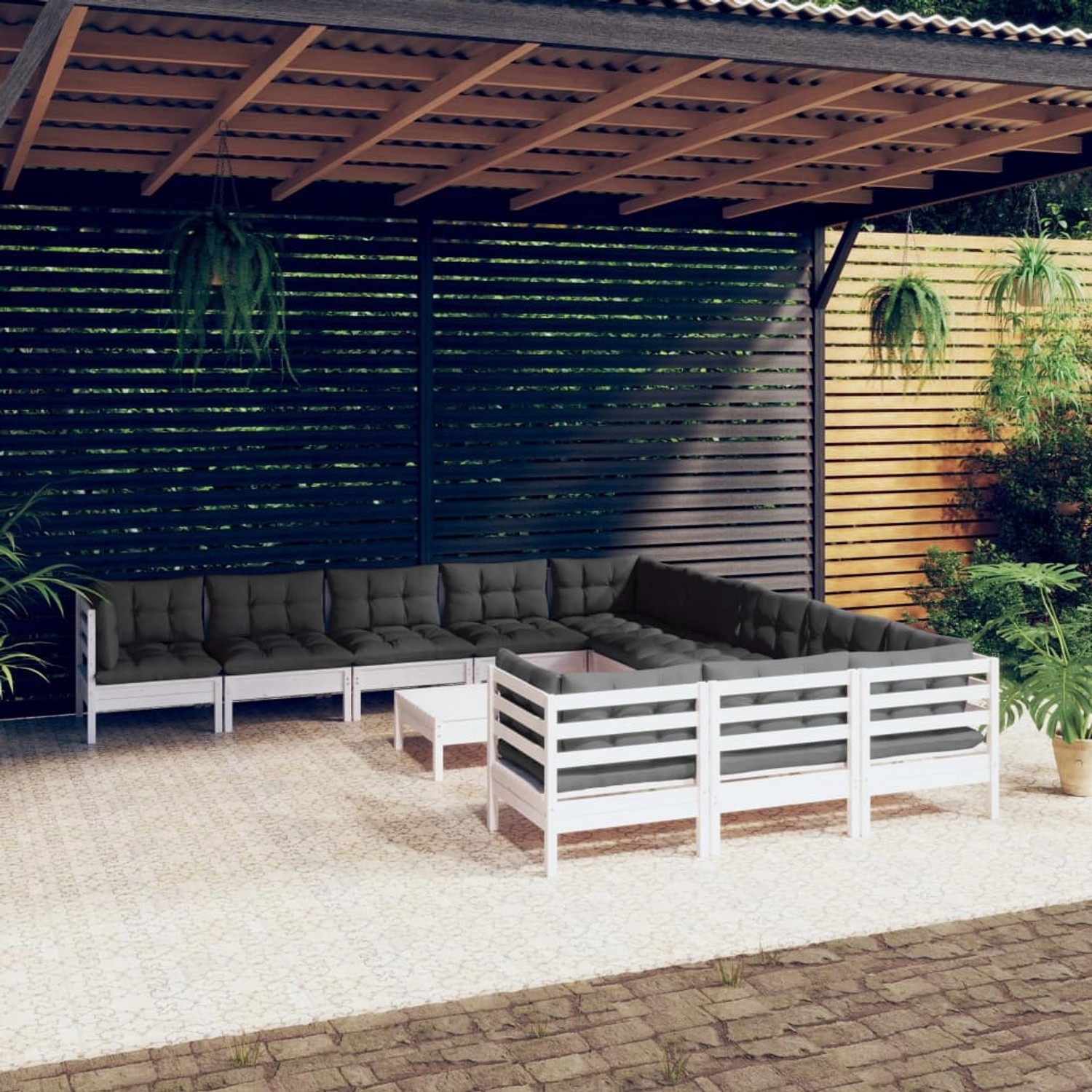 Weißes 12-tlg. Garten-Lounge-Set aus Kiefernholz mit anthrazitfarbenen Kissen unter einer Pergola.