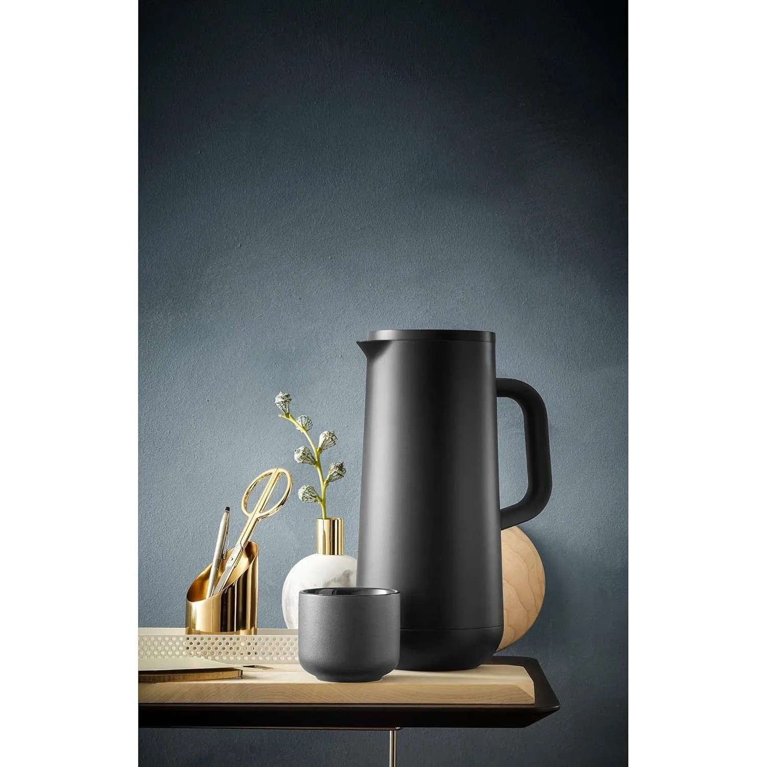 WMF Impulse Isolierkanne 1,0l in mattem Schwarz mit passender Tasse auf Holzplatte. Perfekt für Kaffee & Tee.