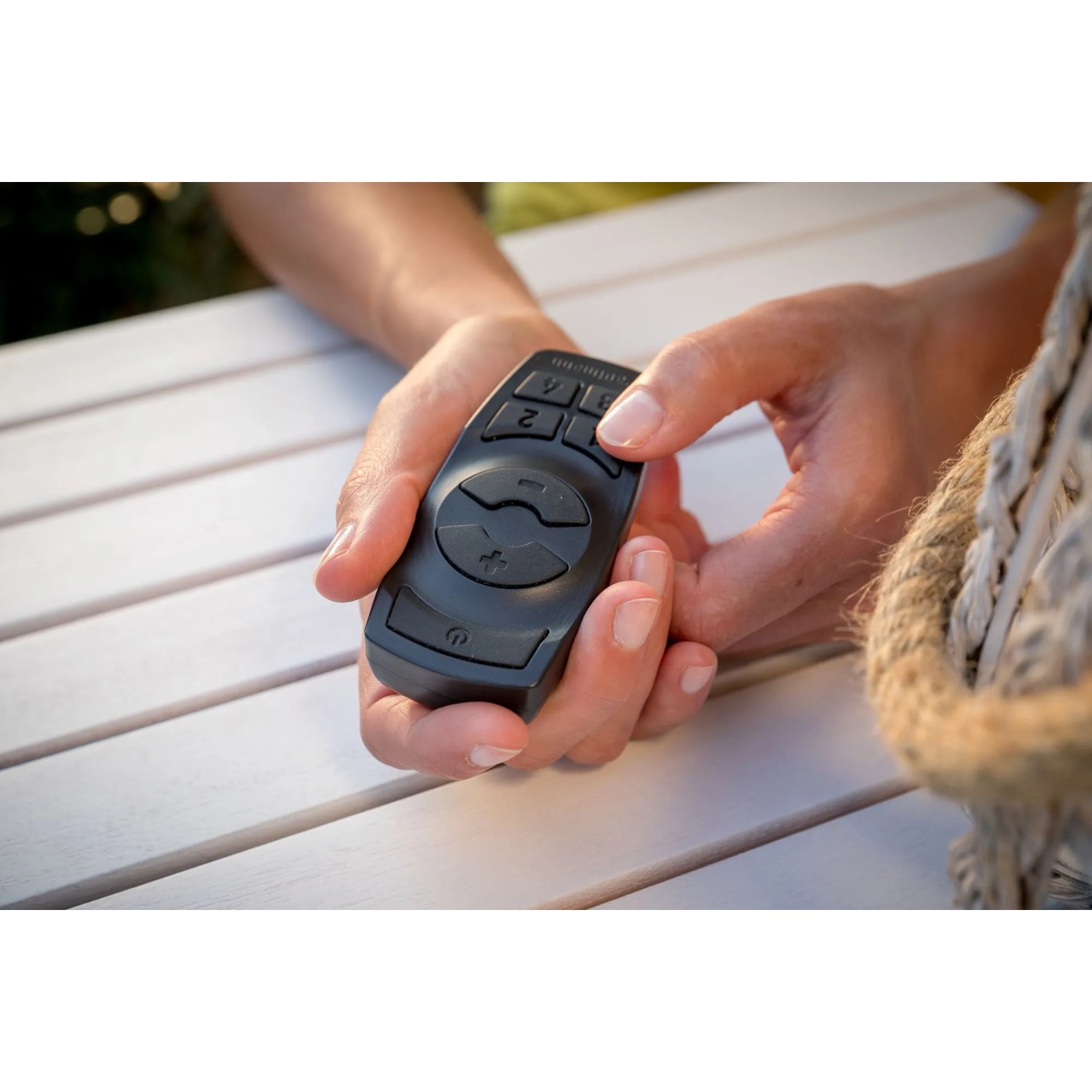 Paulmann Plug & Shine Controller in Schwarz mit Fernbedienung in Händen, zur Steuerung von Außenbeleuchtung.