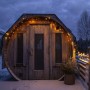 LED Lichtervorhang Eisregen am Holzhaus im Schnee. Warmweiße Außen-Beleuchtung für Haus & Garten.