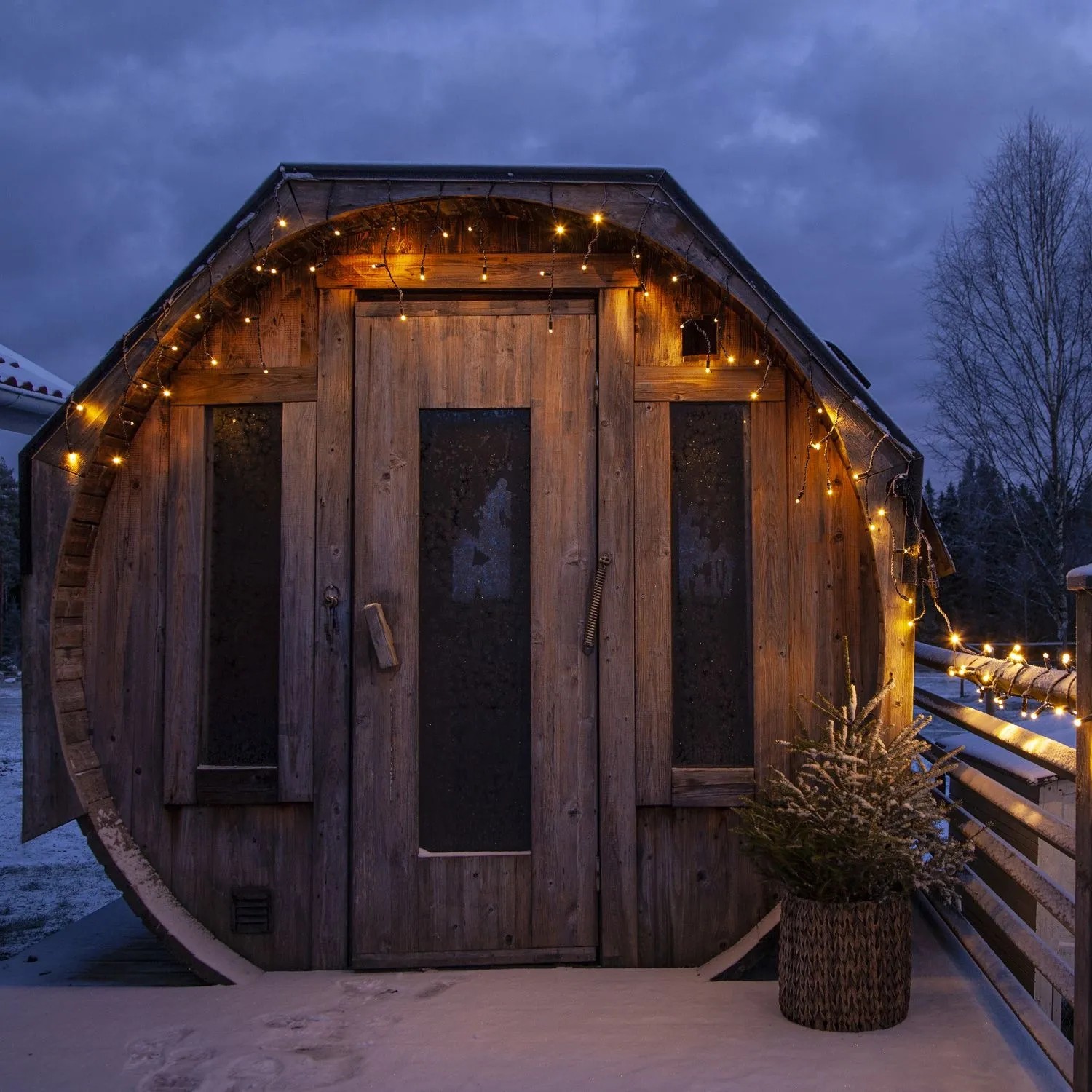 LED Lichtervorhang Eisregen am Holzhaus im Schnee. Warmweiße Außen-Beleuchtung für Haus & Garten.