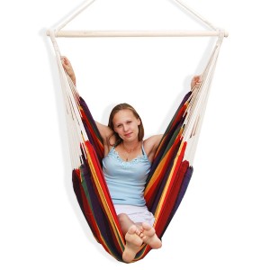 Frau entspannt im AMANKA Hängesessel (Regenbogenfarben). Bequemer Schwebesessel mit Holzstab.