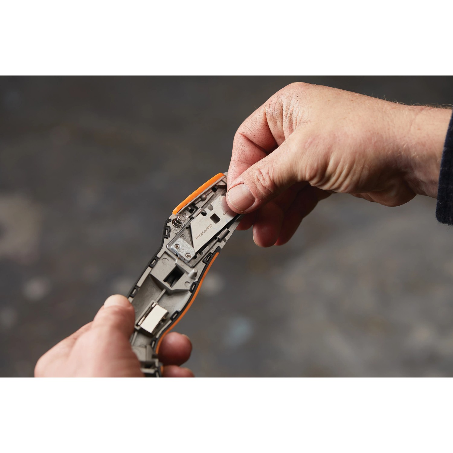 Detailaufnahme: Hände wechseln Klinge am Fiskars Universalmesser CarbonMax™.