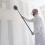 Mann schleift Trockenbauwand mit wolfcraft Teleskopstiel und Rundschleifer Ø 225 mm. Ausziehbar für Überkopfarbeiten.