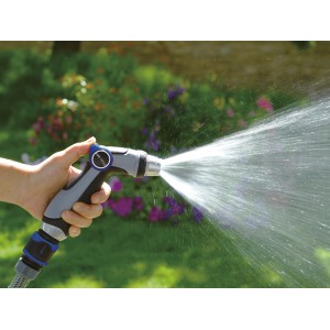 Hand hält regulierbare Gartenspritze, Wasserstrahl im Garten.