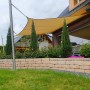 Sandfarbenes Toldoro Sonnensegel Komplettset mit Edelstahl-Halterung im Garten.