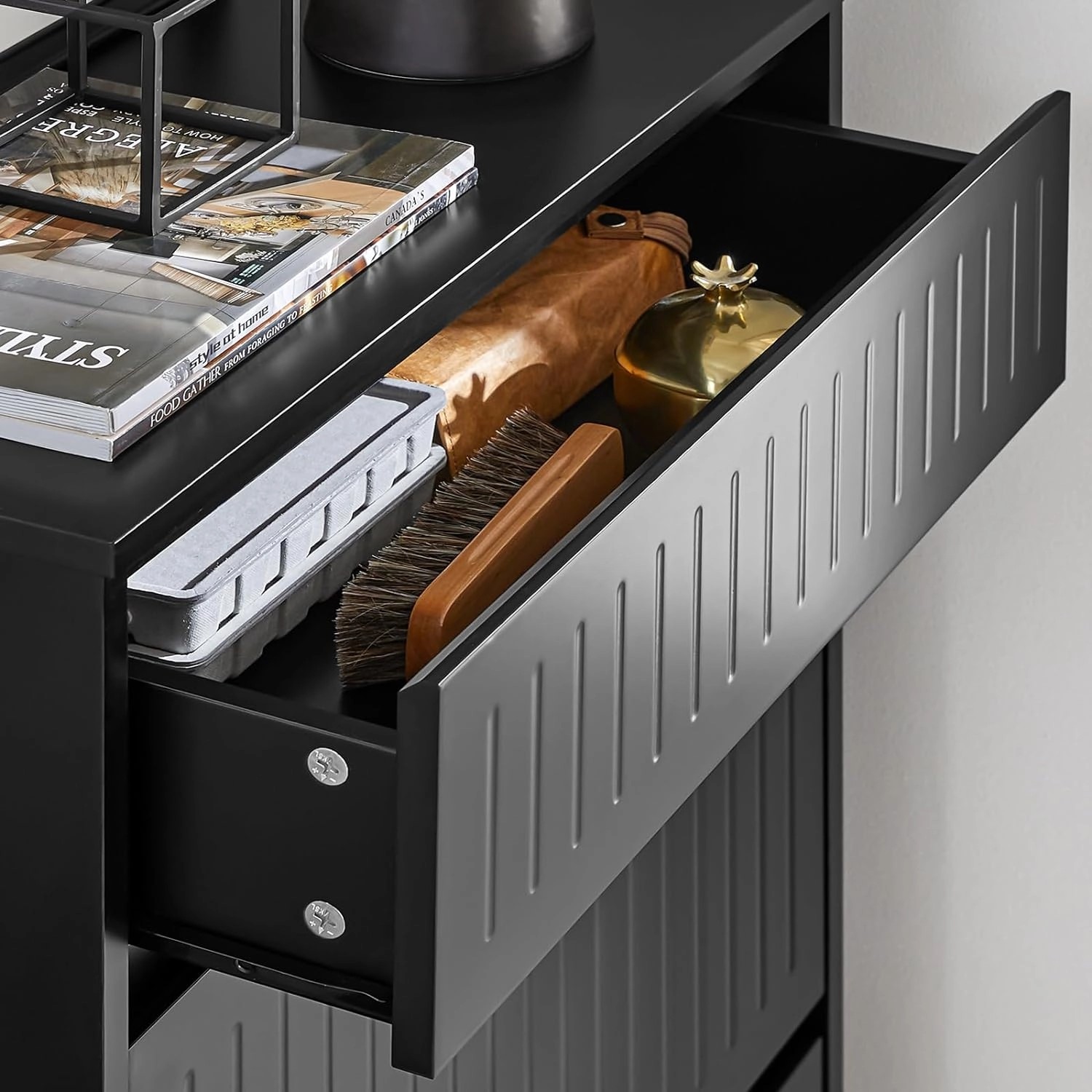 Schwarzer Schuhkipper mit offener Schublade, gefüllt mit Schuhpflegeprodukten.