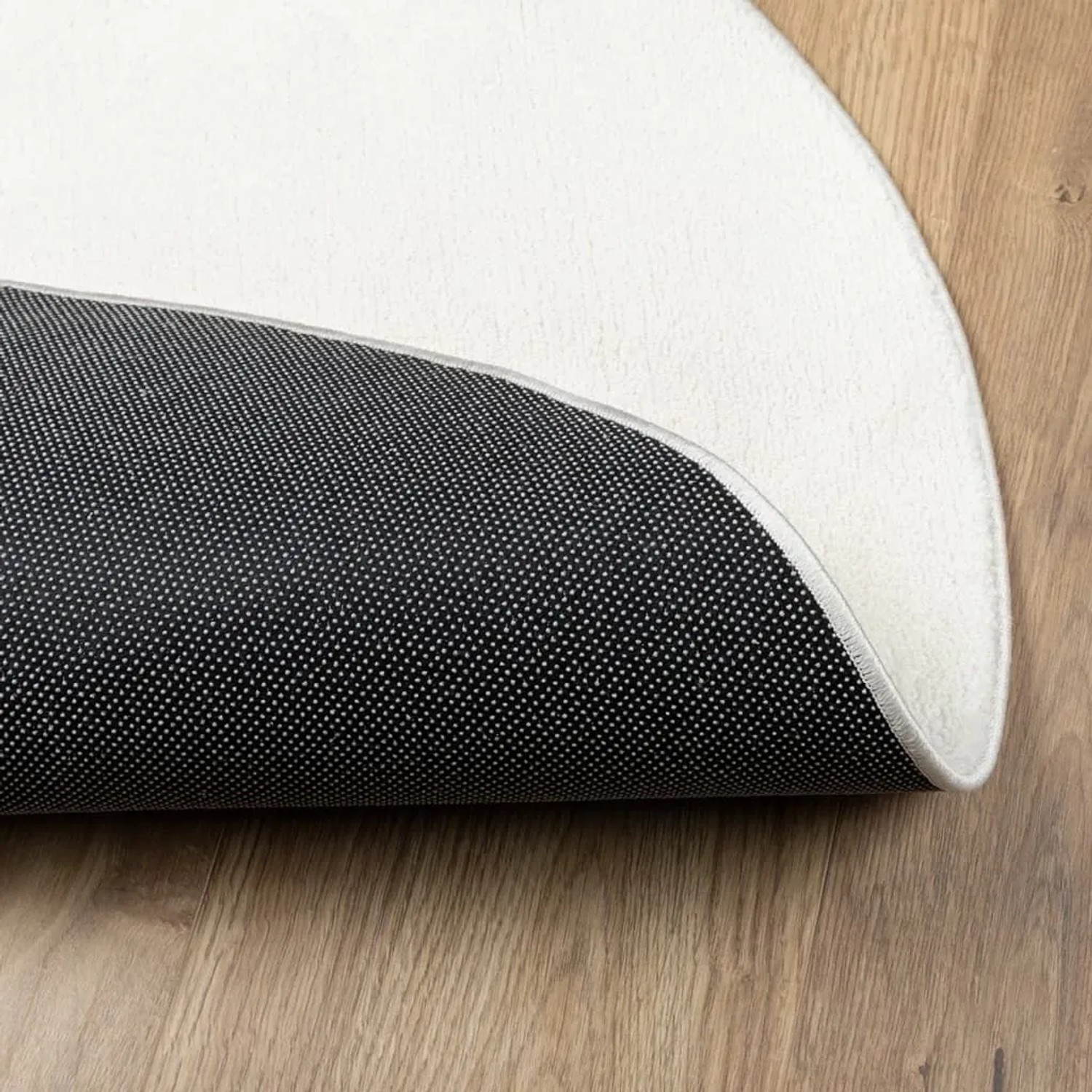 Runder OVIEDO Kurzflor Teppich in Creme, Ø 160 cm, mit weicher Oberfläche und rutschfester Unterseite auf Holz.